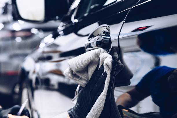 Man worker in car wash polishing car with cloth. Car detailing