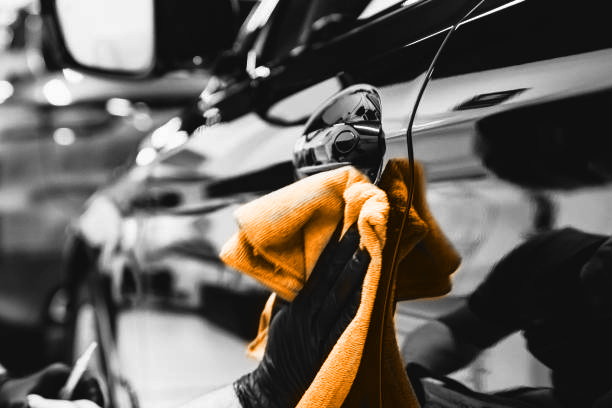 Man worker in car wash polishing car with cloth. Car detailing